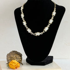 Vintage Sarah Coventry necklace with white ribbed thermoset panels, clear rhinestones, and gold‑tone links, shown from multiple angles to display its mid‑century design.