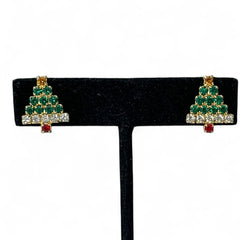 Pair of vintage Sarah Coventry clip-on earrings shaped like Christmas trees, featuring clear and green rhinestones as leaves, a red rhinestone trunk, and a yellow rhinestone star at the top. Gold tone metal with signed clips. Small size, festive design.