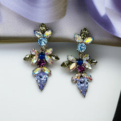 Vintage Schoffel Austria dangle earrings featuring blue, purple, and aurora borealis crystals in silver-tone settings, with floral and teardrop motifs, shown from multiple angles to highlight sparkle, craftsmanship, and signed crown mark.
