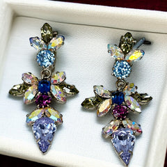 Vintage Schoffel Austria dangle earrings featuring blue, purple, and aurora borealis crystals in silver-tone settings, with floral and teardrop motifs, shown from multiple angles to highlight sparkle, craftsmanship, and signed crown mark.