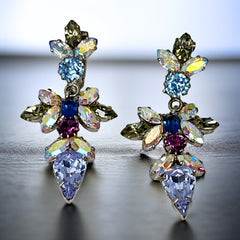 Vintage Schoffel Austria dangle earrings featuring blue, purple, and aurora borealis crystals in silver-tone settings, with floral and teardrop motifs, shown from multiple angles to highlight sparkle, craftsmanship, and signed crown mark.