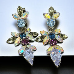 Vintage Schoffel Austria dangle earrings featuring blue, purple, and aurora borealis crystals in silver-tone settings, with floral and teardrop motifs, shown from multiple angles to highlight sparkle, craftsmanship, and signed crown mark.