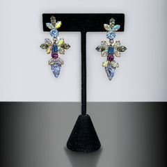 Vintage Schoffel Austria dangle earrings featuring blue, purple, and aurora borealis crystals in silver-tone settings, with floral and teardrop motifs, shown from multiple angles to highlight sparkle, craftsmanship, and signed crown mark.