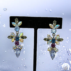 Vintage Schoffel Austria dangle earrings featuring blue, purple, and aurora borealis crystals in silver-tone settings, with floral and teardrop motifs, shown from multiple angles to highlight sparkle, craftsmanship, and signed crown mark.