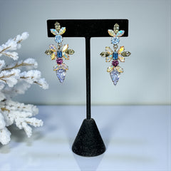Vintage Schoffel Austria dangle earrings featuring blue, purple, and aurora borealis crystals in silver-tone settings, with floral and teardrop motifs, shown from multiple angles to highlight sparkle, craftsmanship, and signed crown mark.