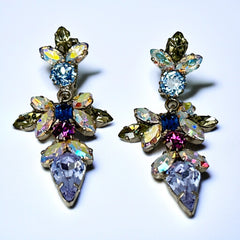 Vintage Schoffel Austria dangle earrings featuring blue, purple, and aurora borealis crystals in silver-tone settings, with floral and teardrop motifs, shown from multiple angles to highlight sparkle, craftsmanship, and signed crown mark.