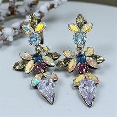 Vintage Schoffel Austria dangle earrings featuring blue, purple, and aurora borealis crystals in silver-tone settings, with floral and teardrop motifs, shown from multiple angles to highlight sparkle, craftsmanship, and signed crown mark.