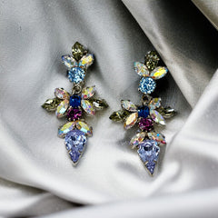 Vintage Schoffel Austria dangle earrings featuring blue, purple, and aurora borealis crystals in silver-tone settings, with floral and teardrop motifs, shown from multiple angles to highlight sparkle, craftsmanship, and signed crown mark.