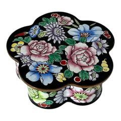 Vintage Seymour Mann flower-shaped trinket box with black enamel exterior, decorated with multicolored floral designs outlined in gold; features a light blue enamel interior and sculpted petal edges.