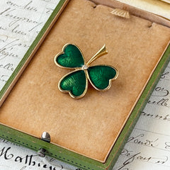 Vintage BJ green enamel shamrock brooch in gold tone with clear rhinestone center, shown in box and on antique French paper.