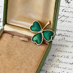 Vintage BJ green enamel shamrock brooch in gold tone with clear rhinestone center, shown in box and on antique French paper.