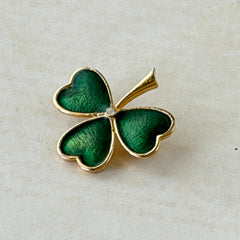 Vintage BJ green enamel shamrock brooch in gold tone with clear rhinestone center, shown in box and on antique French paper.