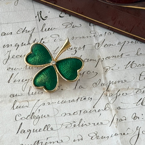 Vintage BJ green enamel shamrock brooch in gold tone with clear rhinestone center, shown in box and on antique French paper.