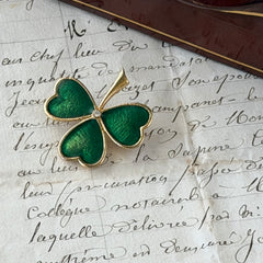 Vintage BJ green enamel shamrock brooch in gold tone with clear rhinestone center, shown in box and on antique French paper.