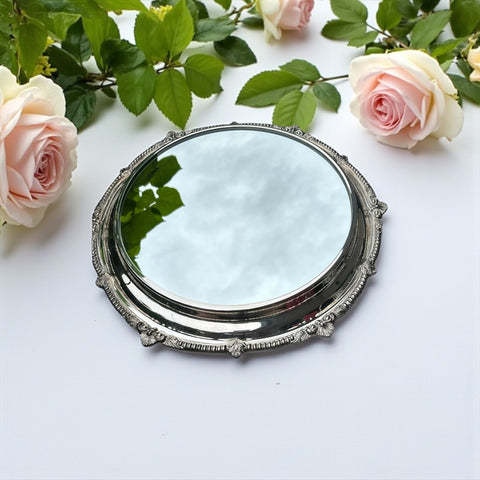 Vintage Sheffield Silver Co. Shrewsbury Plateau round silver-plated tray with mirrored surface and ornate floral scrollwork border; footed design with four decorative legs; shown outdoors with sky and leaves reflected in mirror; very good vintage condition with original packaging and maker’s sticker from Norton, Massachusetts.