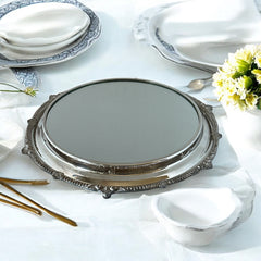 Vintage Sheffield Silver Co. Shrewsbury Plateau round silver-plated tray with mirrored surface and ornate floral scrollwork border; footed design with four decorative legs; shown outdoors with sky and leaves reflected in mirror; very good vintage condition with original packaging and maker’s sticker from Norton, Massachusetts.