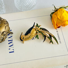 Vintage gold‑tone bird of paradise brooch with navy and green enamel accents, clear pave rhinestones, and a textured metal body, signed Sphinx with model number A2385.