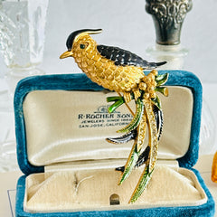 Vintage gold‑tone bird of paradise brooch with navy and green enamel accents, clear pave rhinestones, and a textured metal body, signed Sphinx with model number A2385.