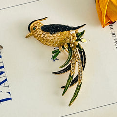 Vintage gold‑tone bird of paradise brooch with navy and green enamel accents, clear pave rhinestones, and a textured metal body, signed Sphinx with model number A2385.