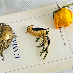 Vintage gold‑tone bird of paradise brooch with navy and green enamel accents, clear pave rhinestones, and a textured metal body, signed Sphinx with model number A2385.