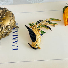 Vintage gold‑tone bird of paradise brooch with navy and green enamel accents, clear pave rhinestones, and a textured metal body, signed Sphinx with model number A2385.