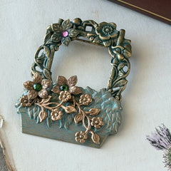 Vintage hand‑painted green and gold tone floral basket brooch with rhinestone accents, shown from multiple angles.