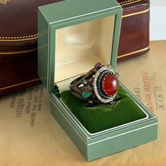 Vintage 1990s Turkish Sultan‑style brass ring with ornate beadwork and cut‑outs, featuring a central carnelian‑colored glass cabochon surrounded by green, ruby, and clear rhinestones on an antique brass setting.