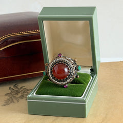 Vintage 1990s Turkish Sultan‑style brass ring with ornate beadwork and cut‑outs, featuring a central carnelian‑colored glass cabochon surrounded by green, ruby, and clear rhinestones on an antique brass setting.