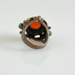 Vintage 1990s Turkish Sultan‑style brass ring with ornate beadwork and cut‑outs, featuring a central carnelian‑colored glass cabochon surrounded by green, ruby, and clear rhinestones on an antique brass setting.