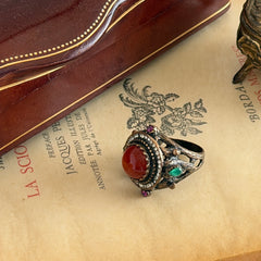 Vintage 1990s Turkish Sultan‑style brass ring with ornate beadwork and cut‑outs, featuring a central carnelian‑colored glass cabochon surrounded by green, ruby, and clear rhinestones on an antique brass setting.