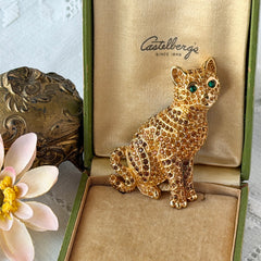 Vintage Swarovski cat brooch from the 1996 Precious Pets collection with hand‑polished gold‑plated setting, topaz and smoked topaz pavé crystals, green cabochon eyes, and honey‑brown enamel back, shown in various angles and lighting.