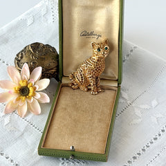 Vintage Swarovski cat brooch from the 1996 Precious Pets collection with hand‑polished gold‑plated setting, topaz and smoked topaz pavé crystals, green cabochon eyes, and honey‑brown enamel back, shown in various angles and lighting.