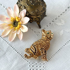 Vintage Swarovski cat brooch from the 1996 Precious Pets collection with hand‑polished gold‑plated setting, topaz and smoked topaz pavé crystals, green cabochon eyes, and honey‑brown enamel back, shown in various angles and lighting.