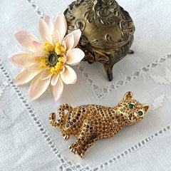 Vintage Swarovski cat brooch from the 1996 Precious Pets collection with hand‑polished gold‑plated setting, topaz and smoked topaz pavé crystals, green cabochon eyes, and honey‑brown enamel back, shown in various angles and lighting.