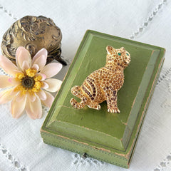 Vintage Swarovski cat brooch from the 1996 Precious Pets collection with hand‑polished gold‑plated setting, topaz and smoked topaz pavé crystals, green cabochon eyes, and honey‑brown enamel back, shown in various angles and lighting.