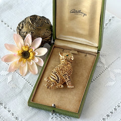 Vintage Swarovski cat brooch from the 1996 Precious Pets collection with hand‑polished gold‑plated setting, topaz and smoked topaz pavé crystals, green cabochon eyes, and honey‑brown enamel back, shown in various angles and lighting.