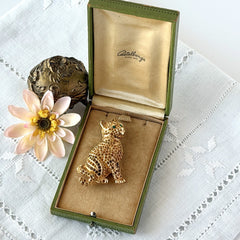 Vintage Swarovski cat brooch from the 1996 Precious Pets collection with hand‑polished gold‑plated setting, topaz and smoked topaz pavé crystals, green cabochon eyes, and honey‑brown enamel back, shown in various angles and lighting.