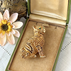 Vintage Swarovski cat brooch from the 1996 Precious Pets collection with hand‑polished gold‑plated setting, topaz and smoked topaz pavé crystals, green cabochon eyes, and honey‑brown enamel back, shown in various angles and lighting.
