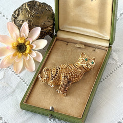 Vintage Swarovski cat brooch from the 1996 Precious Pets collection with hand‑polished gold‑plated setting, topaz and smoked topaz pavé crystals, green cabochon eyes, and honey‑brown enamel back, shown in various angles and lighting.