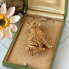 Vintage Swarovski cat brooch from the 1996 Precious Pets collection with hand‑polished gold‑plated setting, topaz and smoked topaz pavé crystals, green cabochon eyes, and honey‑brown enamel back, shown in various angles and lighting.
