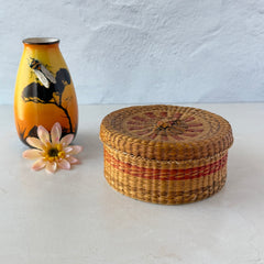 Vintage round sweetgrass basket with lid featuring a red and black woven pattern, shown from multiple angles to highlight its craftsmanship and natural texture.