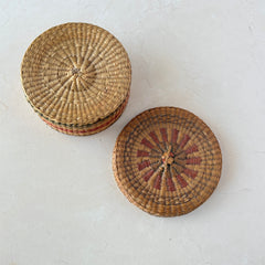 Vintage round sweetgrass basket with lid featuring a red and black woven pattern, shown from multiple angles to highlight its craftsmanship and natural texture.