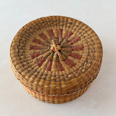Vintage round sweetgrass basket with lid featuring a red and black woven pattern, shown from multiple angles to highlight its craftsmanship and natural texture.