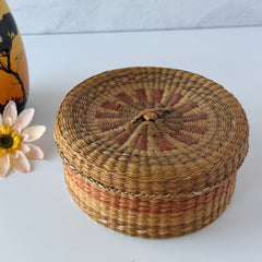 Vintage round sweetgrass basket with lid featuring a red and black woven pattern, shown from multiple angles to highlight its craftsmanship and natural texture.