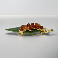 Vintage Swoboda brooch featuring a carved green jade leaf and a cluster of round carnelian berries set in gold‑tone metal, shown from multiple angles to highlight its details and signature.