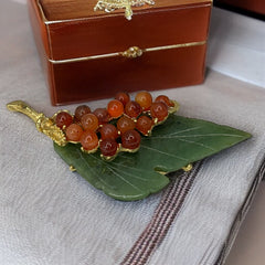 Vintage Swoboda brooch featuring a carved green jade leaf and a cluster of round carnelian berries set in gold‑tone metal, shown from multiple angles to highlight its details and signature.