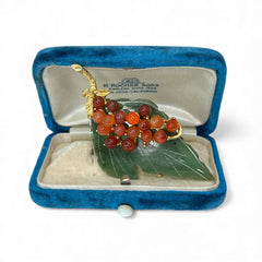 Vintage Swoboda brooch featuring a carved green jade leaf and a cluster of round carnelian berries set in gold‑tone metal, shown from multiple angles to highlight its details and signature.