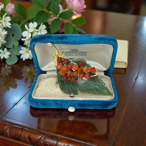 Vintage Swoboda brooch featuring a carved green jade leaf and a cluster of round carnelian berries set in gold‑tone metal, shown from multiple angles to highlight its details and signature.