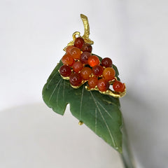 Vintage Swoboda brooch featuring a carved green jade leaf and a cluster of round carnelian berries set in gold‑tone metal, shown from multiple angles to highlight its details and signature.