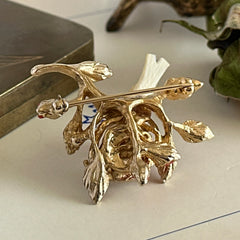 Vintage Swoboda bird nest brooch with a painted bone bird, faux pearl eggs, coral‑colored stone chips, and gold‑tone metal branch detailing.